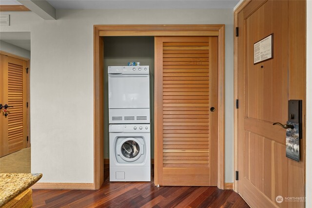 clothes washing area featuring stacked washer / drying machine and dark hardwood / wood-style floors