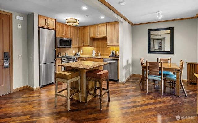 kitchen featuring a breakfast bar area, appliances with stainless steel finishes, dark hardwood / wood-style floors, sink, and a center island