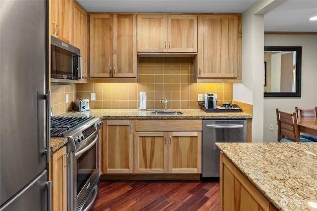 kitchen with dark wood-type flooring, stainless steel appliances, backsplash, sink, and light stone countertops