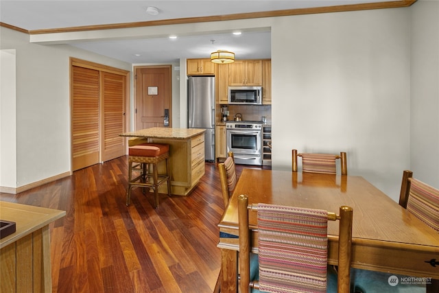 kitchen with dark wood-type flooring, a breakfast bar, a center island, appliances with stainless steel finishes, and tasteful backsplash