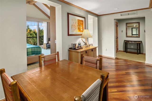 dining space featuring dark hardwood / wood-style flooring, crown molding, and vaulted ceiling