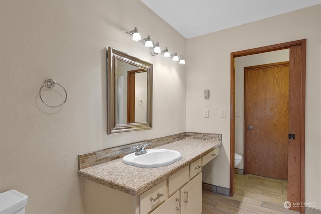 bathroom with vanity, toilet, and hardwood / wood-style flooring