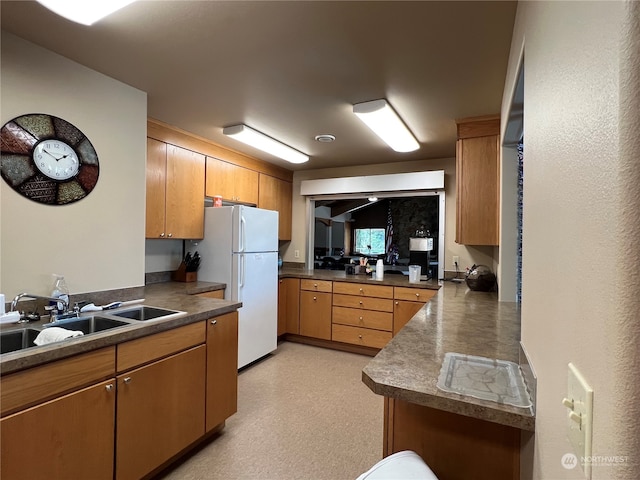 kitchen with kitchen peninsula, sink, and white refrigerator