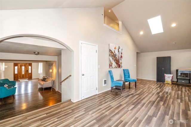 unfurnished room featuring hardwood / wood-style floors, high vaulted ceiling, and a skylight