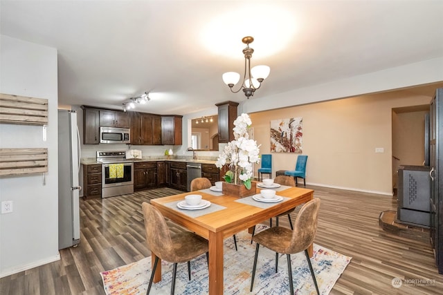 dining space with dark hardwood / wood-style floors, sink, and a notable chandelier