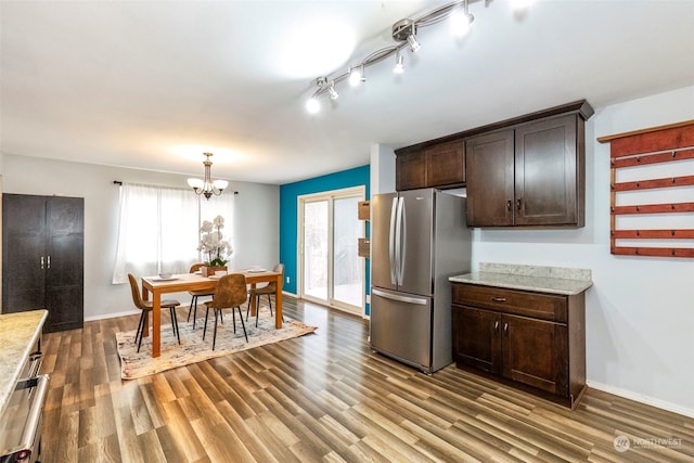 kitchen with stainless steel fridge, hanging light fixtures, dark brown cabinets, dark hardwood / wood-style flooring, and a chandelier