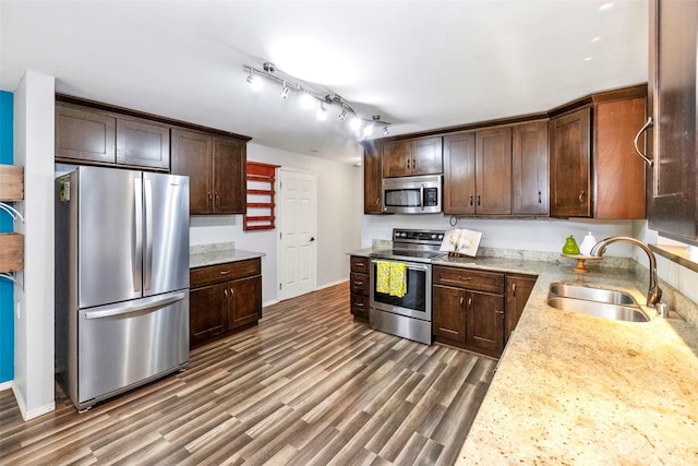 kitchen featuring appliances with stainless steel finishes, sink, dark hardwood / wood-style flooring, light stone counters, and dark brown cabinetry