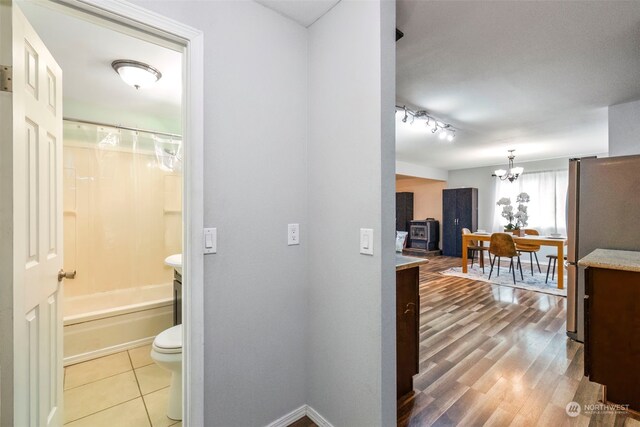 interior space featuring hardwood / wood-style flooring, shower / tub combo with curtain, an inviting chandelier, and toilet