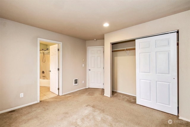 unfurnished bedroom featuring light carpet, ensuite bath, and a closet