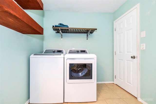 clothes washing area with washing machine and dryer and light tile patterned floors