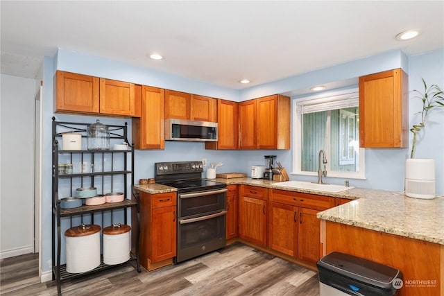 kitchen with light stone countertops, sink, black / electric stove, and hardwood / wood-style flooring