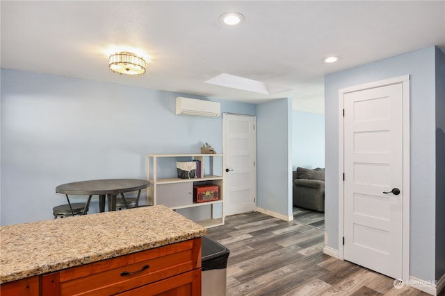 kitchen featuring dark hardwood / wood-style floors, a wall mounted AC, and light stone countertops