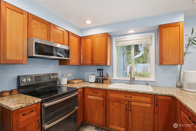 kitchen featuring sink, light stone countertops, and stainless steel appliances