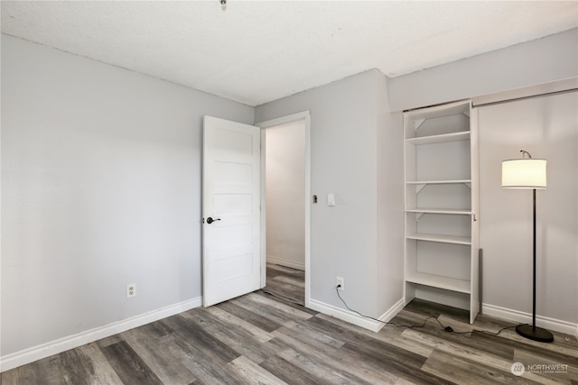 unfurnished bedroom featuring a textured ceiling, wood-type flooring, and a closet