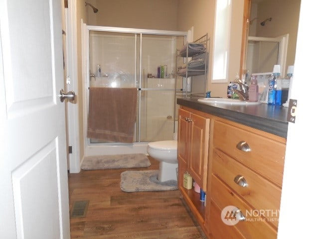 bathroom featuring vanity, toilet, walk in shower, and hardwood / wood-style floors