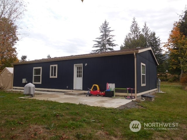 back of property with a yard and a patio