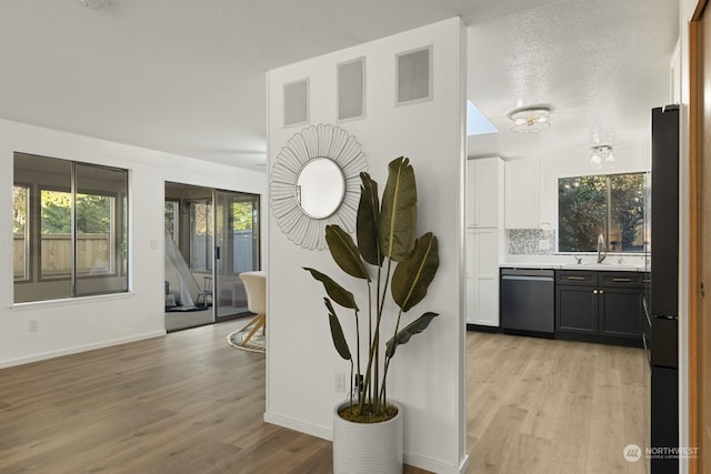 details with stainless steel dishwasher, wood-type flooring, sink, and decorative backsplash