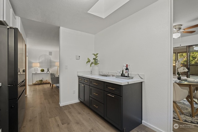 bathroom featuring hardwood / wood-style flooring, ceiling fan, vanity, and a skylight