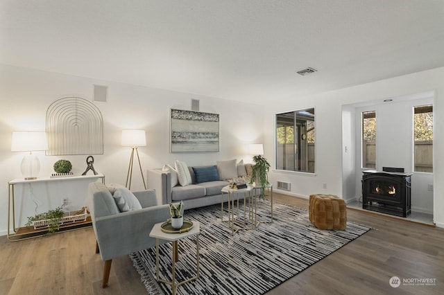 living room with wood-type flooring, a healthy amount of sunlight, and a wood stove