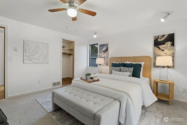 carpeted bedroom with a spacious closet and ceiling fan