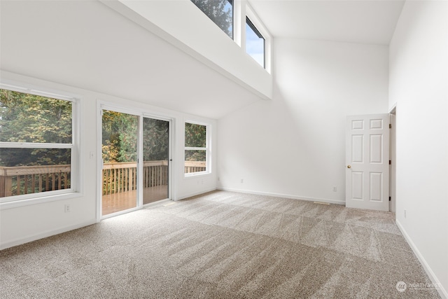 unfurnished living room with beamed ceiling, a healthy amount of sunlight, light colored carpet, and high vaulted ceiling