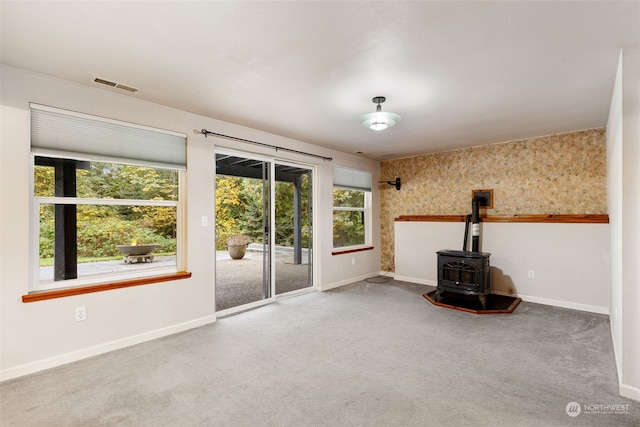 unfurnished living room featuring carpet flooring and a wood stove