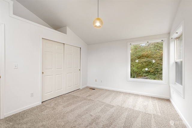 unfurnished bedroom with vaulted ceiling, light carpet, and a closet