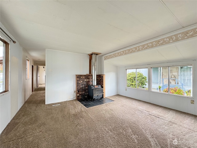 unfurnished living room featuring carpet floors and a wood stove