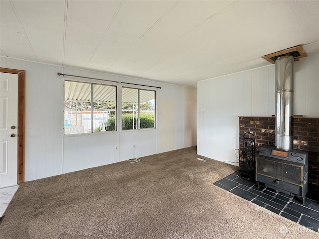 unfurnished living room featuring a wood stove and dark carpet