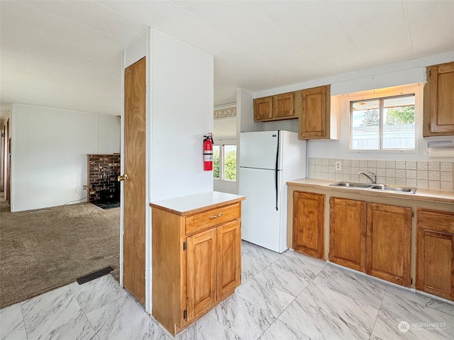 kitchen with light colored carpet, tasteful backsplash, sink, and white refrigerator