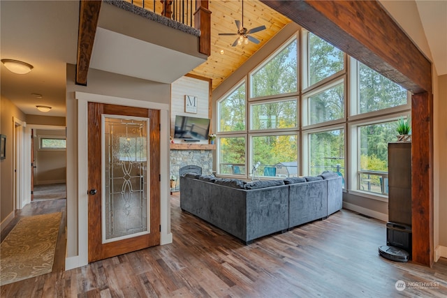 unfurnished living room with dark wood-type flooring, a fireplace, high vaulted ceiling, and ceiling fan