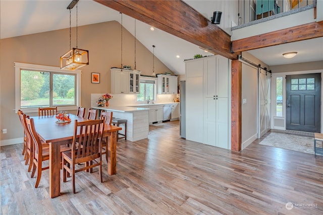 dining space featuring a barn door, high vaulted ceiling, beamed ceiling, light hardwood / wood-style floors, and sink