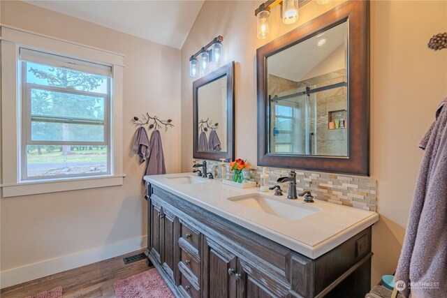 bathroom featuring vanity, backsplash, vaulted ceiling, and a shower with door