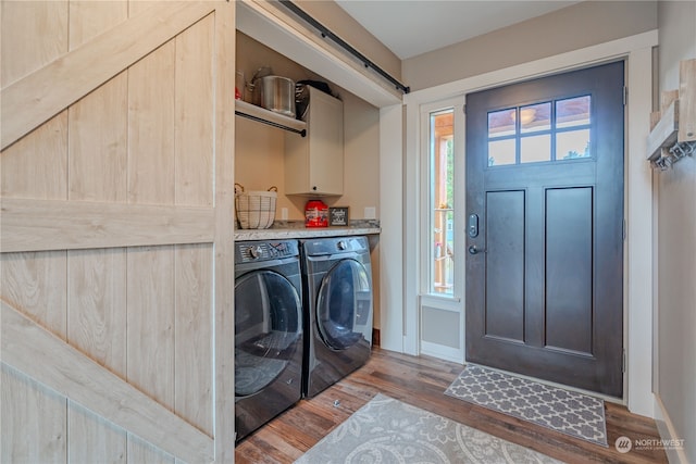 laundry room with cabinets, independent washer and dryer, dark hardwood / wood-style floors, and a barn door