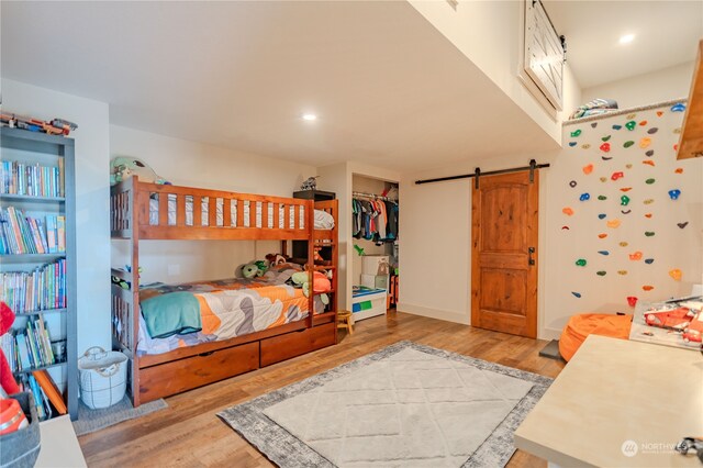 bedroom with a spacious closet, a closet, light wood-type flooring, and a barn door