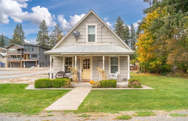 bungalow featuring a porch, a front lawn, and metal roof