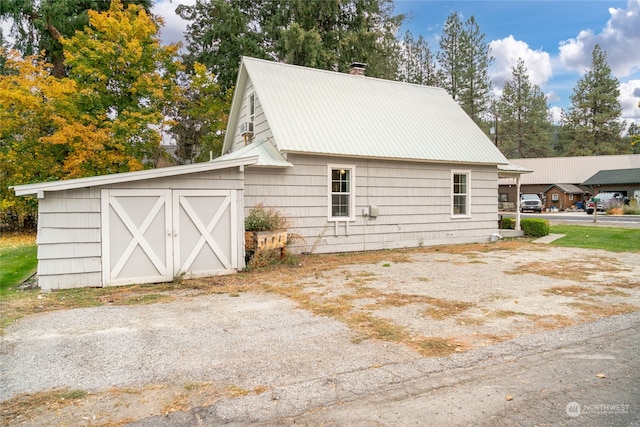 view of side of home featuring a chimney and metal roof