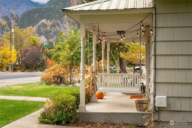 view of patio featuring a porch, a mountain view, and a wooded view