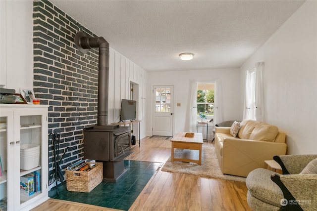 living room featuring a wood stove, wood-type flooring, and a textured ceiling