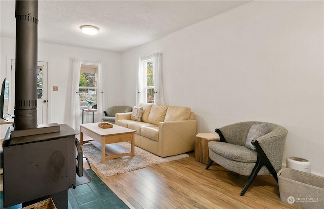living room featuring a wood stove, a textured ceiling, and light wood finished floors