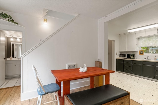 dining area with a textured ceiling and light wood-style flooring