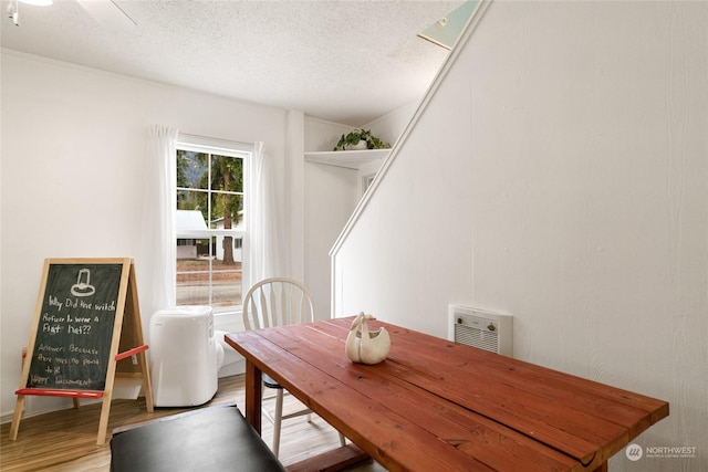 dining area featuring wood finished floors and a textured ceiling