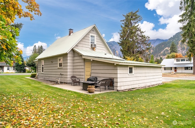 rear view of property featuring a fire pit, a yard, a mountain view, and a patio