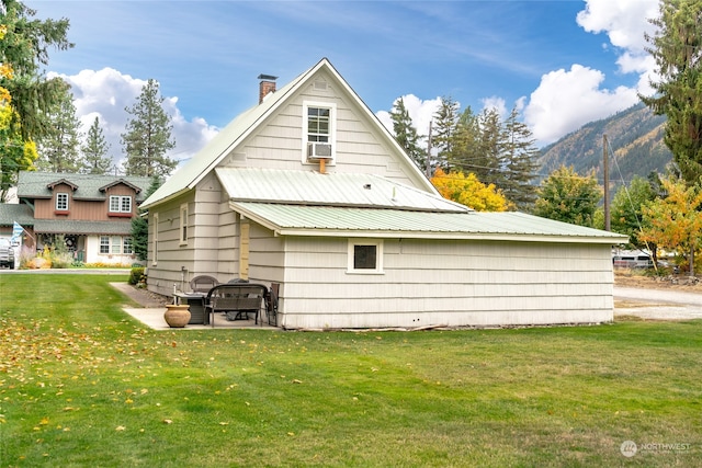 back of property featuring metal roof, a lawn, a chimney, and a mountain view