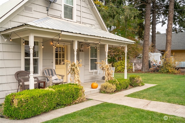 view of front facade with covered porch, metal roof, and a front lawn