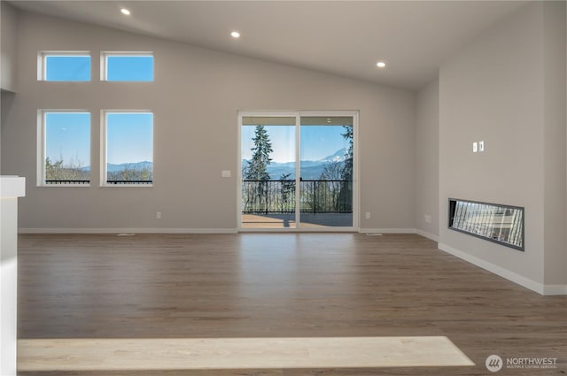 unfurnished living room with a glass covered fireplace, recessed lighting, wood finished floors, and baseboards