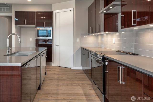 kitchen featuring black electric range, wall chimney exhaust hood, modern cabinets, and a sink