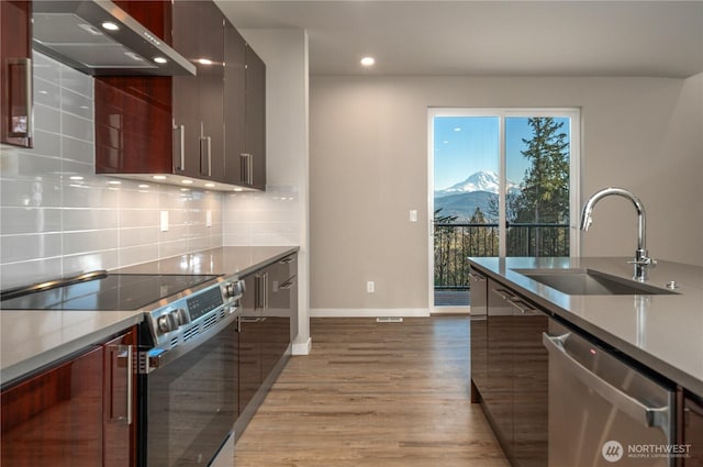 kitchen with light wood-style flooring, a sink, appliances with stainless steel finishes, decorative backsplash, and modern cabinets