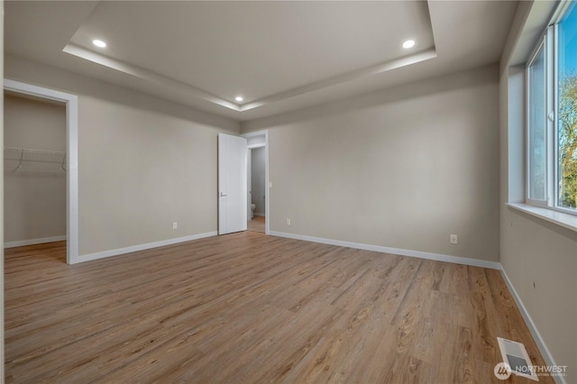 unfurnished bedroom featuring baseboards, a tray ceiling, and recessed lighting