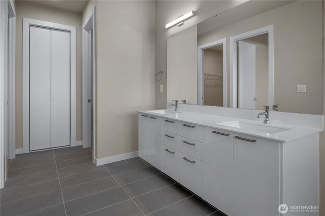 full bath with double vanity, baseboards, a sink, and tile patterned floors